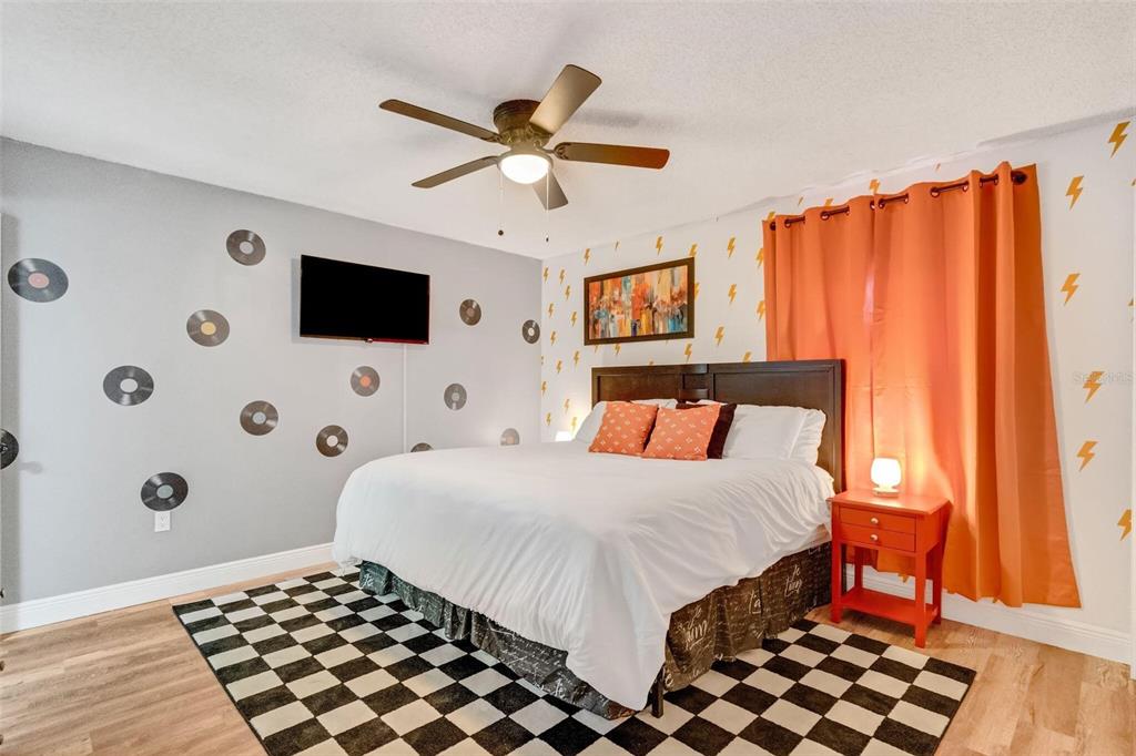 A bedroom features a checkered rug, vinyl record wall decals, lightning bolt wallpaper, and orange curtains — 3357 TIMBERLINE ROAD W, WINTER HAVEN, FL