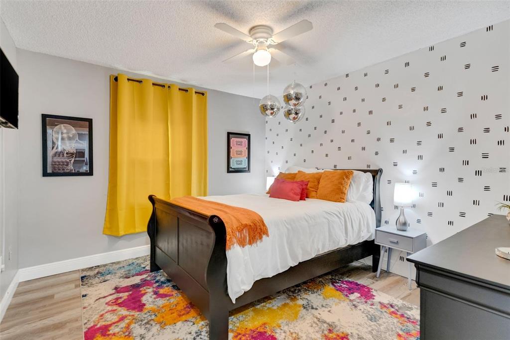 A bedroom features a dark wood bed, patterned wallpaper, yellow curtains, and a colorful rug — 3357 TIMBERLINE ROAD W, WINTER HAVEN, FL
