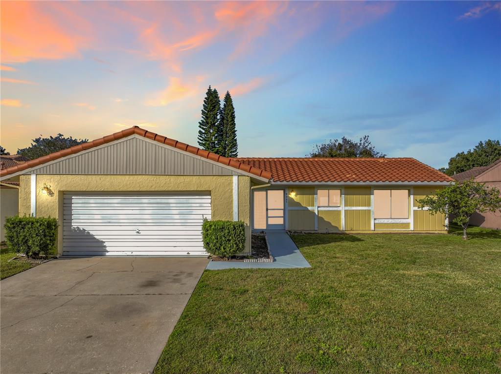 A single-story house with a yellow exterior, a tiled roof, and a white garage door — 5321 WILLIAMSPORT DRIVE, ORLANDO, FL