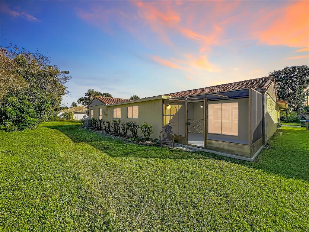 A single-story house with a screened-in porch and a large grassy yard at sunset — 5321 WILLIAMSPORT DRIVE, ORLANDO, FL
