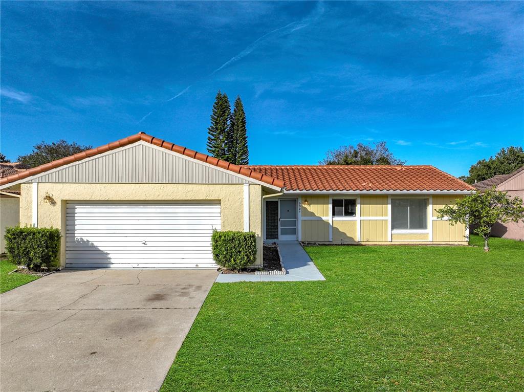 A single-story house with a yellow exterior, white garage door, and a tiled roof — 5321 WILLIAMSPORT DRIVE, ORLANDO, FL