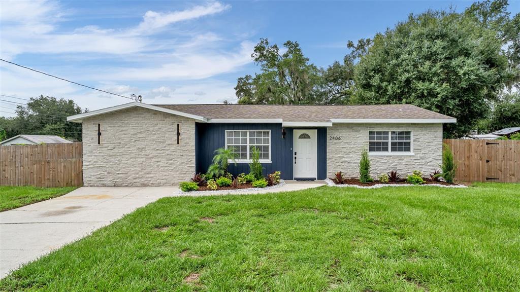 A single-story house features a stone facade, dark blue siding, and a white front door — 2406 FUTCH ROAD, LAKELAND, FL