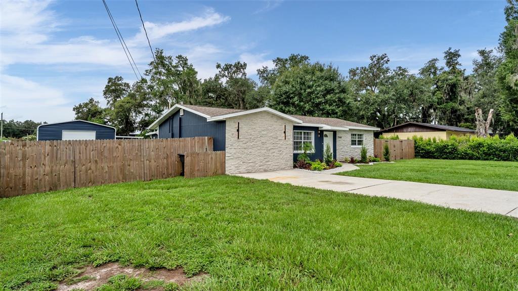 A single-story house with blue siding and stone veneer features a concrete driveway and lawn — 2406 FUTCH ROAD, LAKELAND, FL