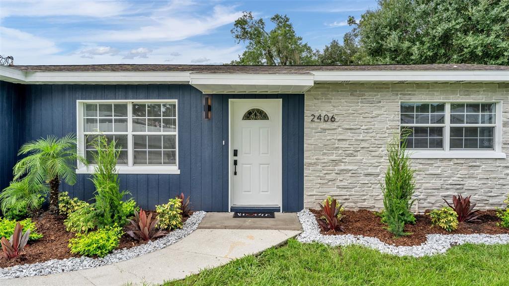 The exterior of a house features blue vertical siding, a stone facade, and a white door — 2406 FUTCH ROAD, LAKELAND, FL