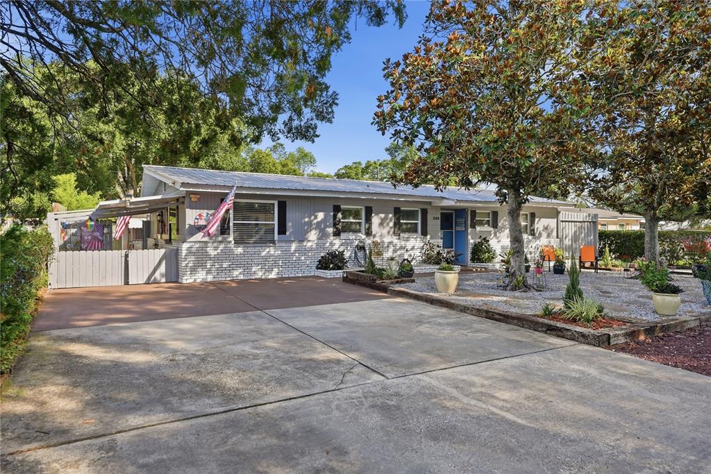 A single-story house with a gray exterior, brick base, metal roof, and a concrete driveway — 240 N DEVON AVENUE, WINTER SPRINGS, FL