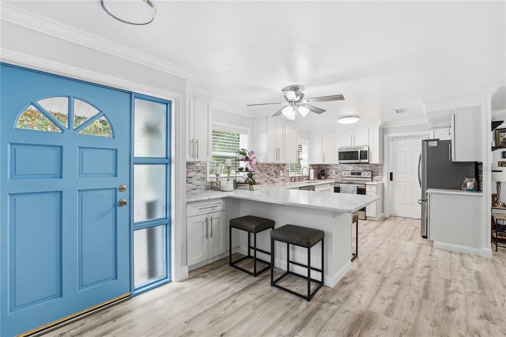 A kitchen with white cabinets, a marble-topped breakfast bar, and a bright blue front door — 240 N DEVON AVENUE, WINTER SPRINGS, FL