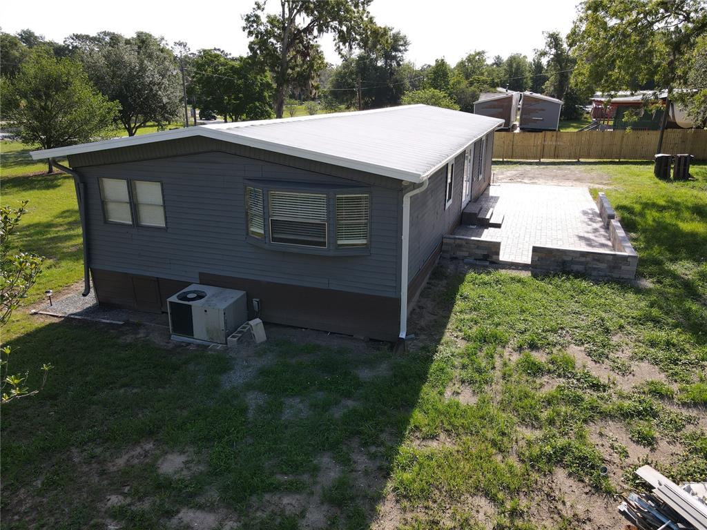 An exterior view of a gray manufactured home with a white roof and paved patio — 17524 MEDLEY AVENUE, SPRING HILL, FL