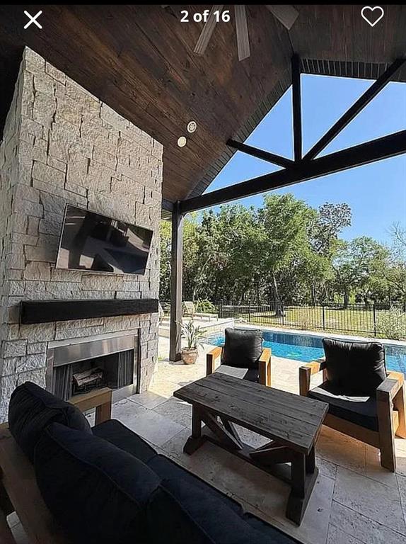A covered outdoor patio features a stone fireplace, a television, and seating overlooking a pool — 1781 TAYLOR ROAD, PORT ORANGE, FL