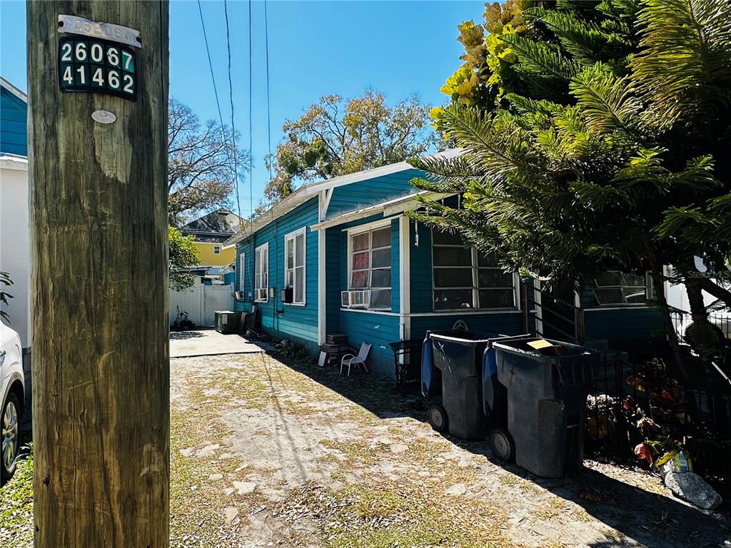 A side view of a blue house with a gravel driveway and two trash bins — 2415 MARCONI STREET, TAMPA, FL