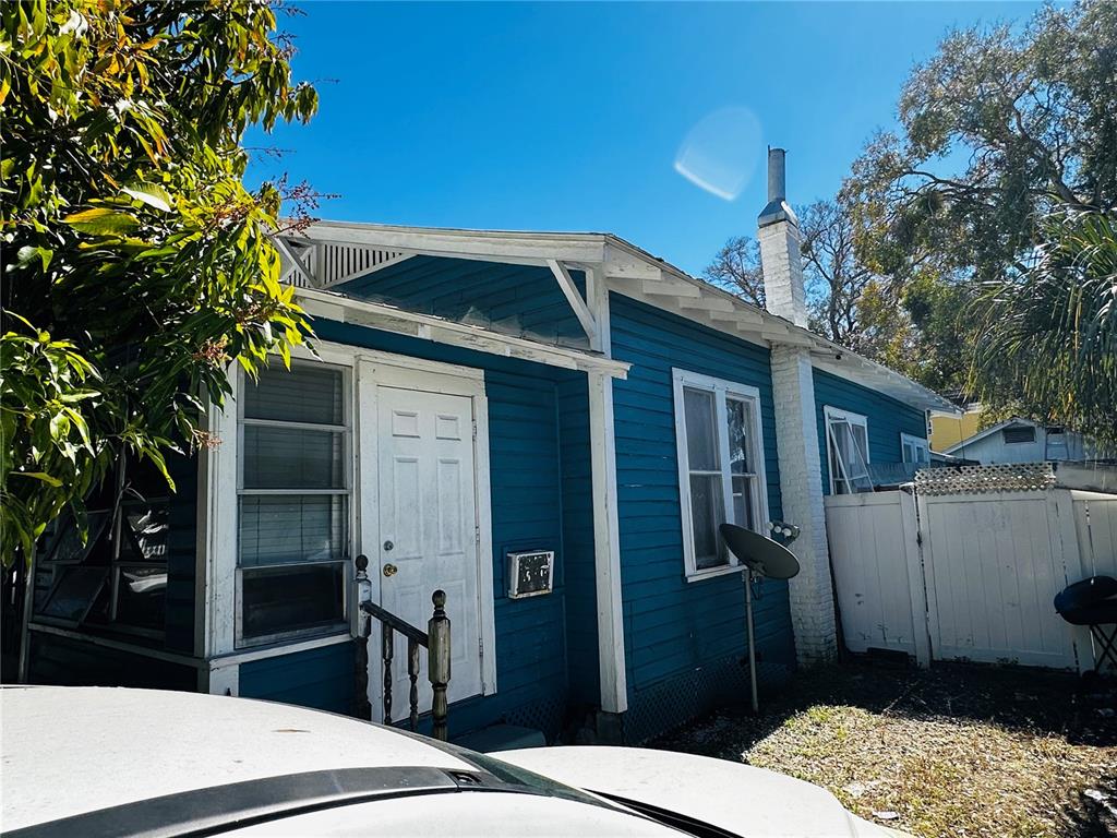 A blue, single-story house with white trim, a white front door, and a brick chimney — 2415 MARCONI STREET, TAMPA, FL