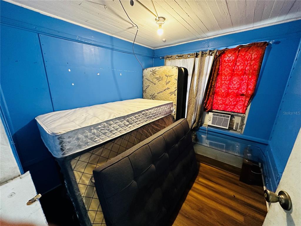 A bedroom with blue walls, wood-look flooring, a mattress, and a dark upholstered headboard — 2415 MARCONI STREET, TAMPA, FL