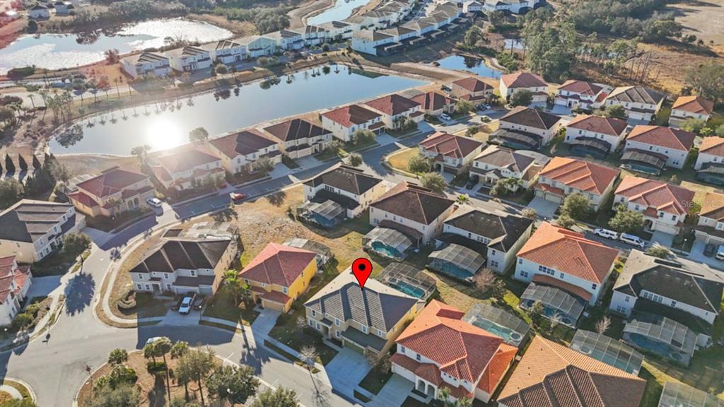 An aerial view shows a suburban neighborhood with houses, swimming pools, and a large lake — 6009 BROAD OAK DRIVE, DAVENPORT, FL