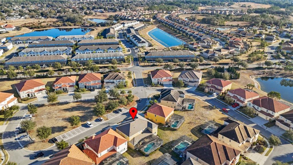 An aerial view shows a residential neighborhood with houses, swimming pools, and a nearby pond — 6009 BROAD OAK DRIVE, DAVENPORT, FL