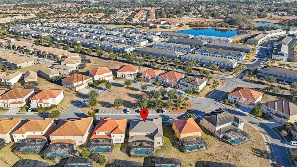 An aerial view shows a suburban neighborhood with houses, swimming pools, and a central pond — 6009 BROAD OAK DRIVE, DAVENPORT, FL