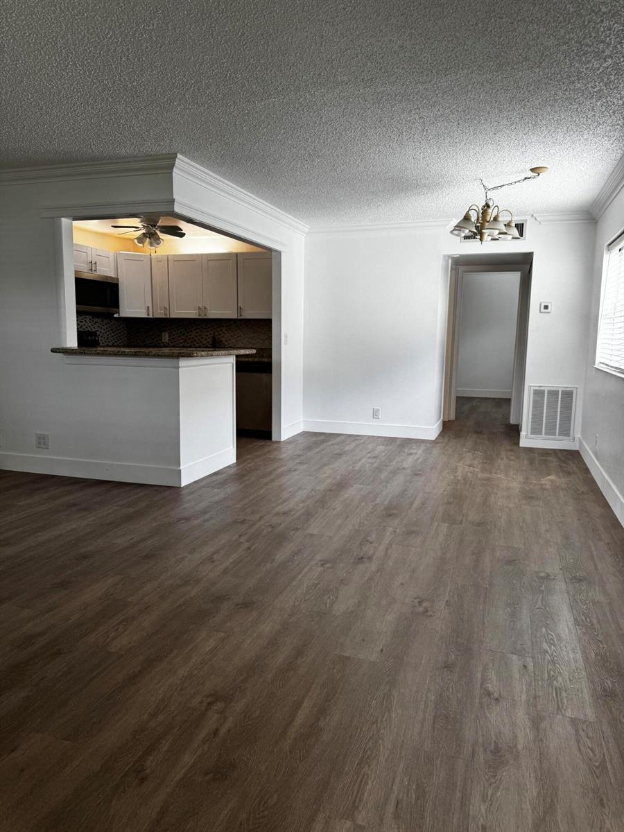 A living room with wood-look flooring, white walls, and an open kitchen with a breakfast bar — 103 Saxony C, Delray Beach FL 33446, DELRAY BEACH, FL