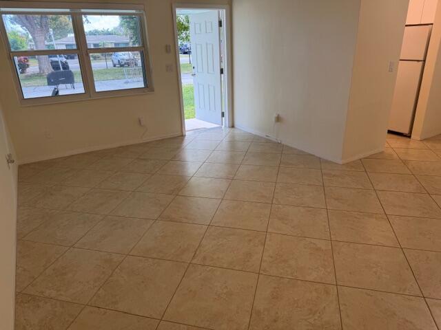 An interior view of a room with beige tile flooring, a large window, and an open door — 3801 NE 22nd Terrace # 12, Lighthouse Point FL 33064, LIGHTHOUSE POINT, FL