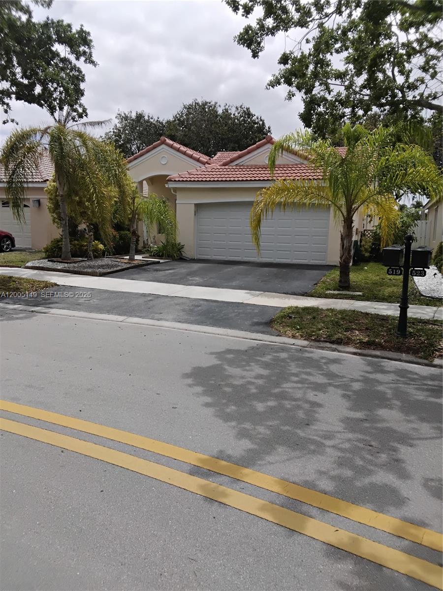 A single-story house with a two-car garage, tile roof, and palm trees in the front yard — 519 Talavera Rd, Weston FL 33326, WESTON, FL