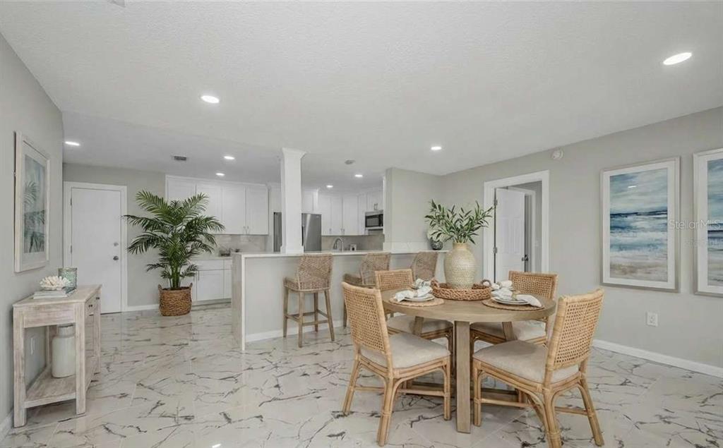 A dining area with a round table and chairs next to a kitchen with white cabinets — 100 BLUFF VIEW DRIVE UNIT 604C, BELLEAIR BLUFFS, FL