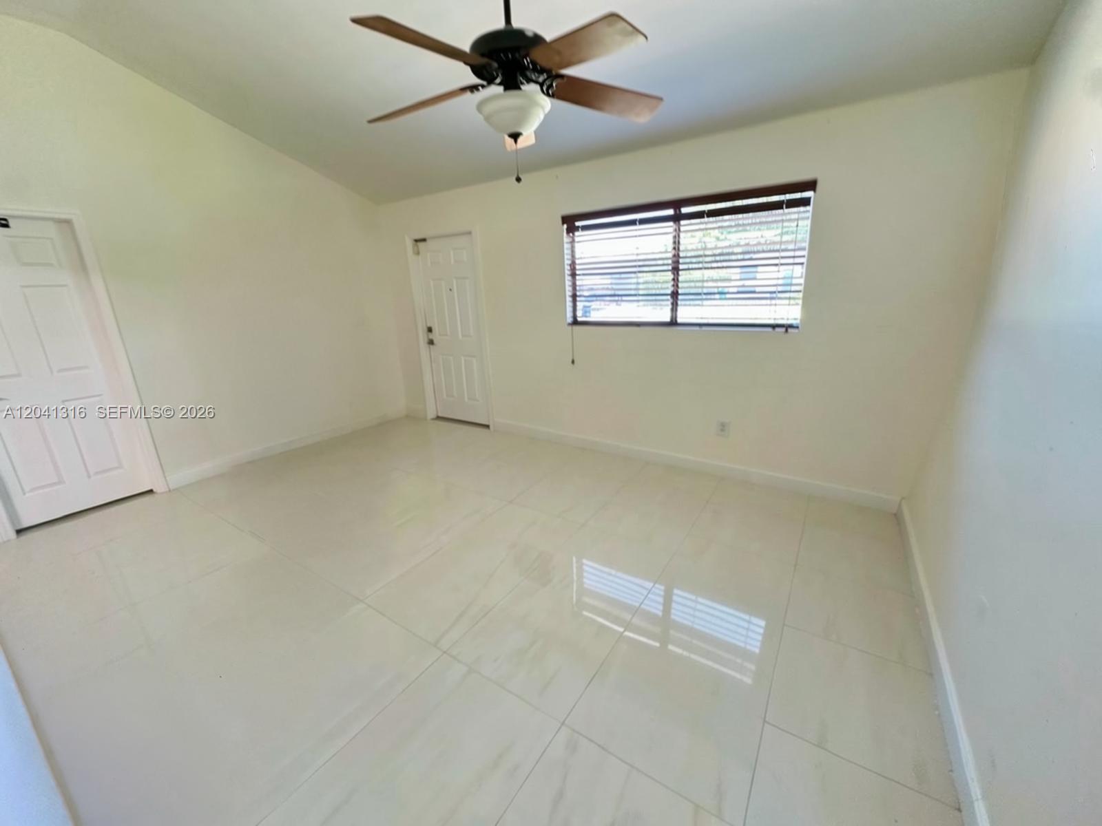 An empty room features white tile flooring, a ceiling fan, and a window with blinds — 10015 SW 213th Ter, Cutler Bay FL 33189, CUTLER BAY, FL