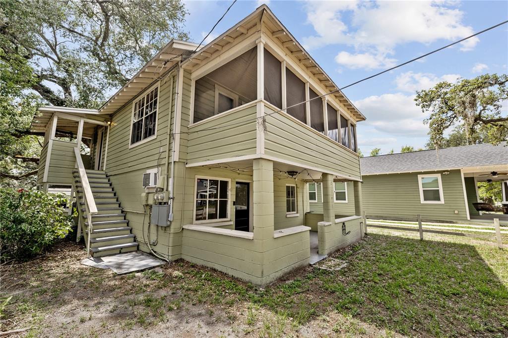 A two-story house with green siding, an exterior staircase, and a screened-in upper porch — 5914 N OLA AVENUE, TAMPA, FL