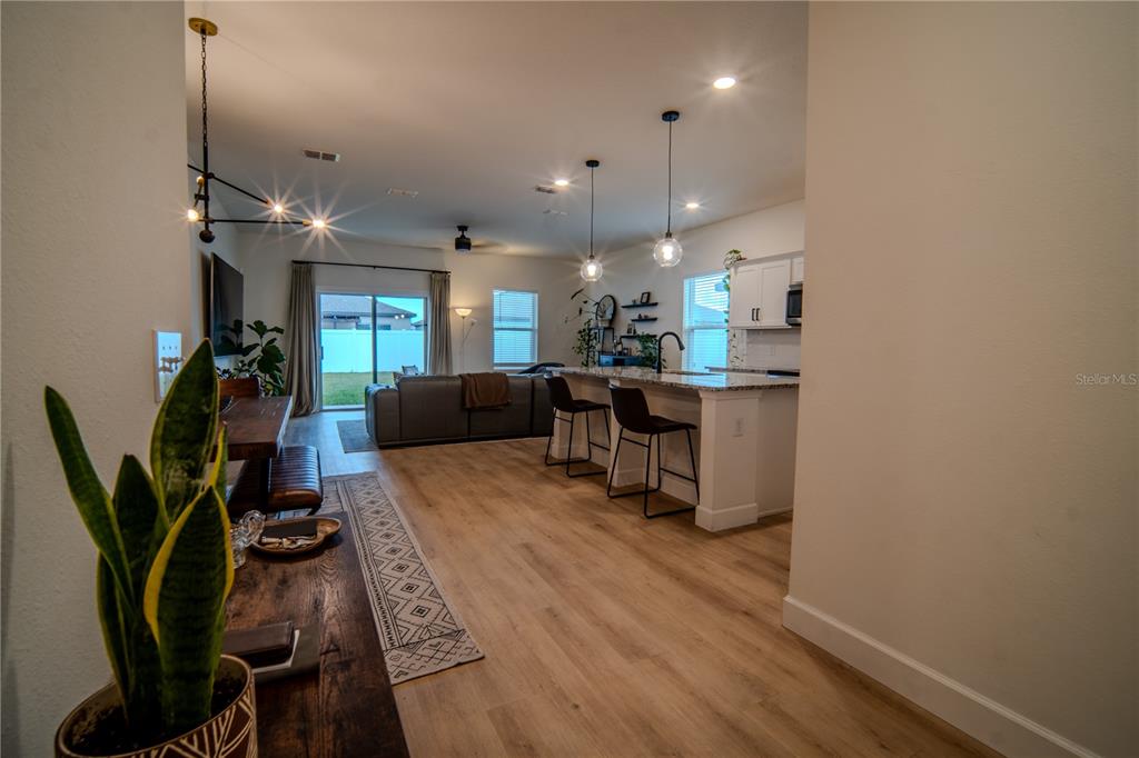 An open-concept living area features a kitchen with white cabinets, an island, and wood flooring — 5859 HERDER ROAD, ST CLOUD, FL