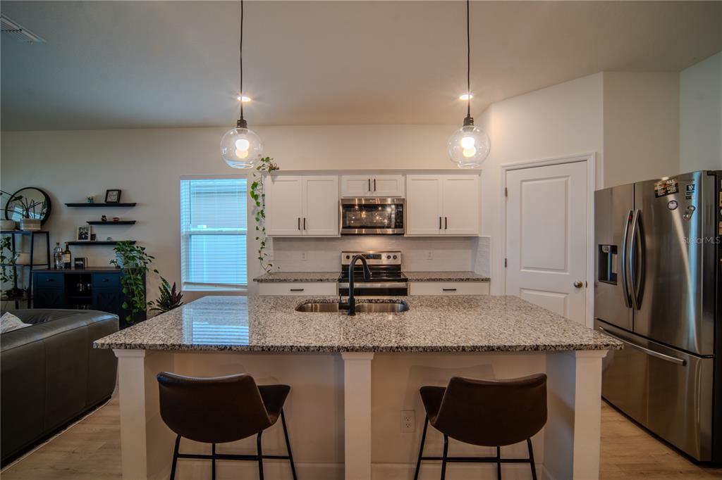 A living room features light wood flooring, a ceiling fan, a sofa, and sliding glass doors — 5859 HERDER ROAD, ST CLOUD, FL
