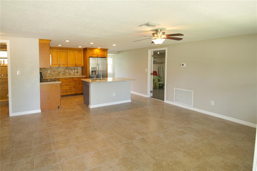 An open-concept kitchen and living area features tile flooring, wood cabinets, and a kitchen island — 4632 SALVIA STREET, NEW PORT RICHEY, FL