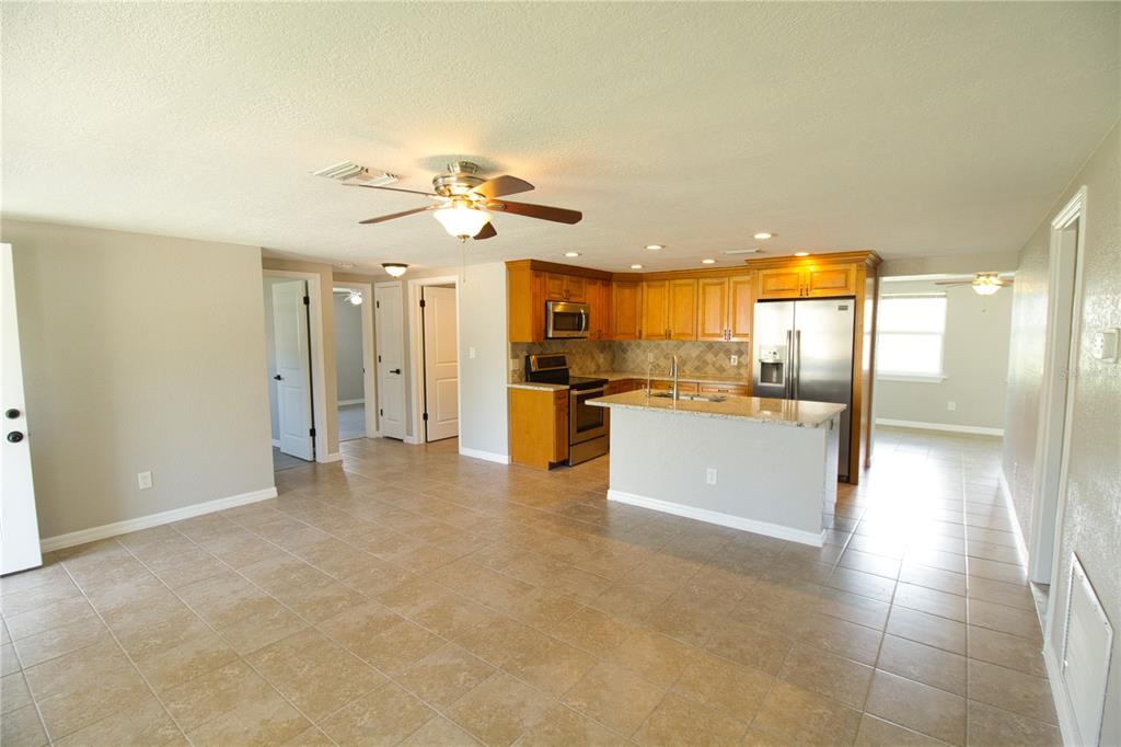 An open-concept kitchen with wood cabinets, stainless steel appliances, and tile flooring — 4632 SALVIA STREET, NEW PORT RICHEY, FL