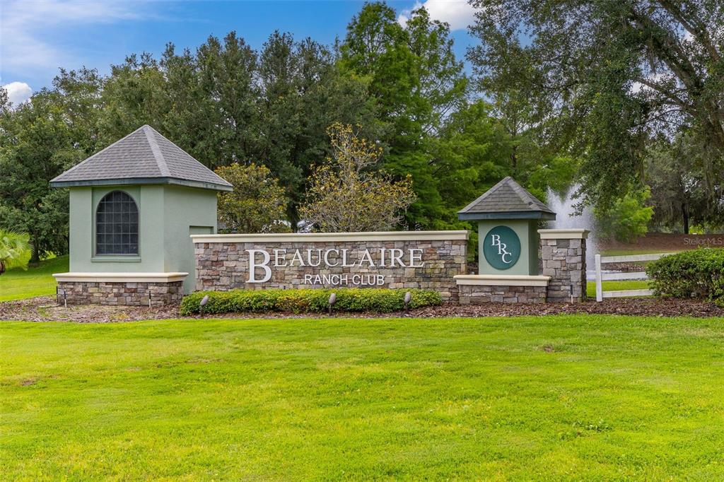 A stone and stucco entrance sign for Beauclaire Ranch Club sits on a grassy lawn — 27037 GRAND OAK LANE, TAVARES, FL