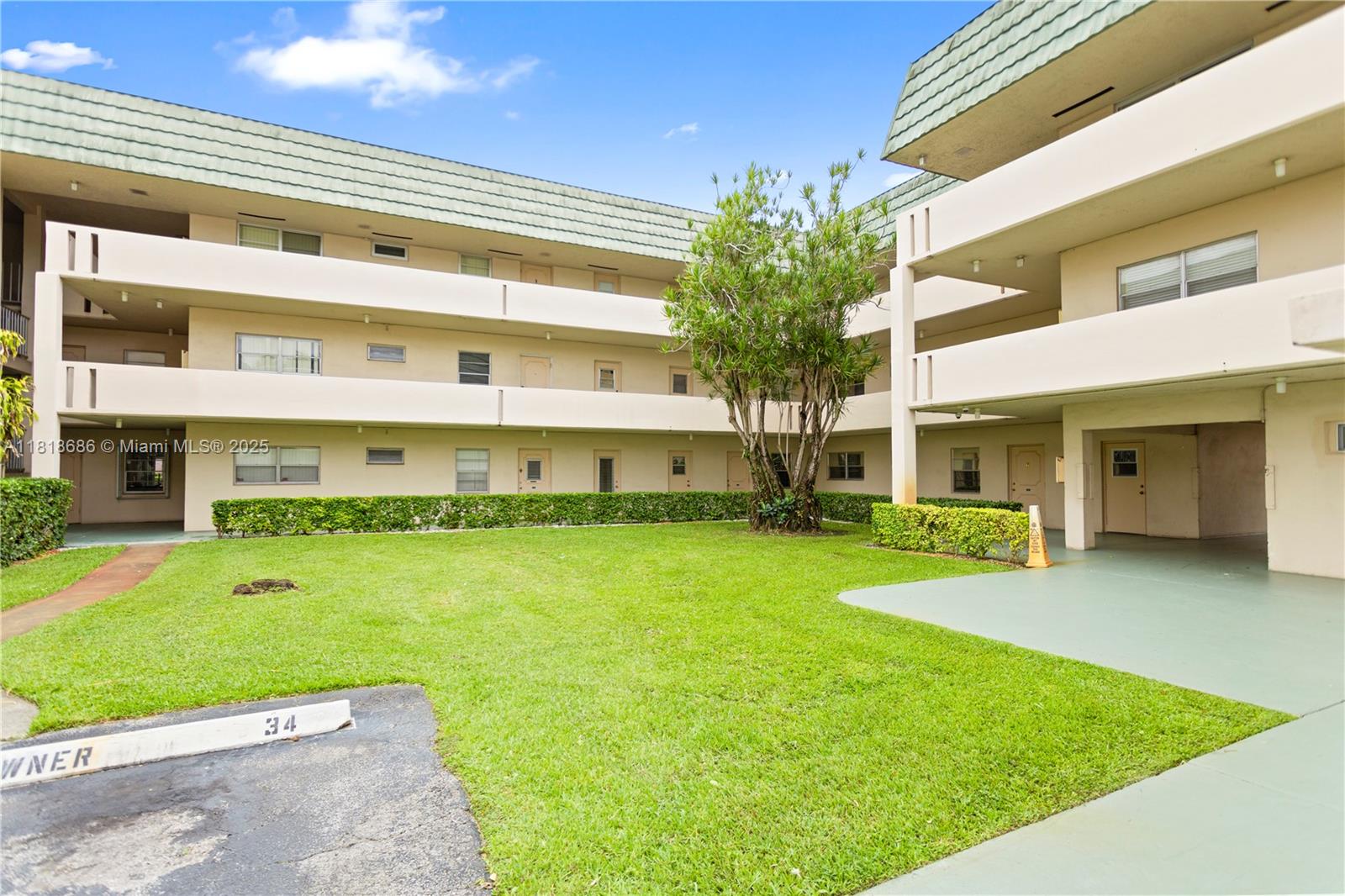 A multi-story apartment building exterior features a central lawn, landscaping, and covered walkways — 5790 Stirling # 212, Hollywood FL 33021, HOLLYWOOD, FL