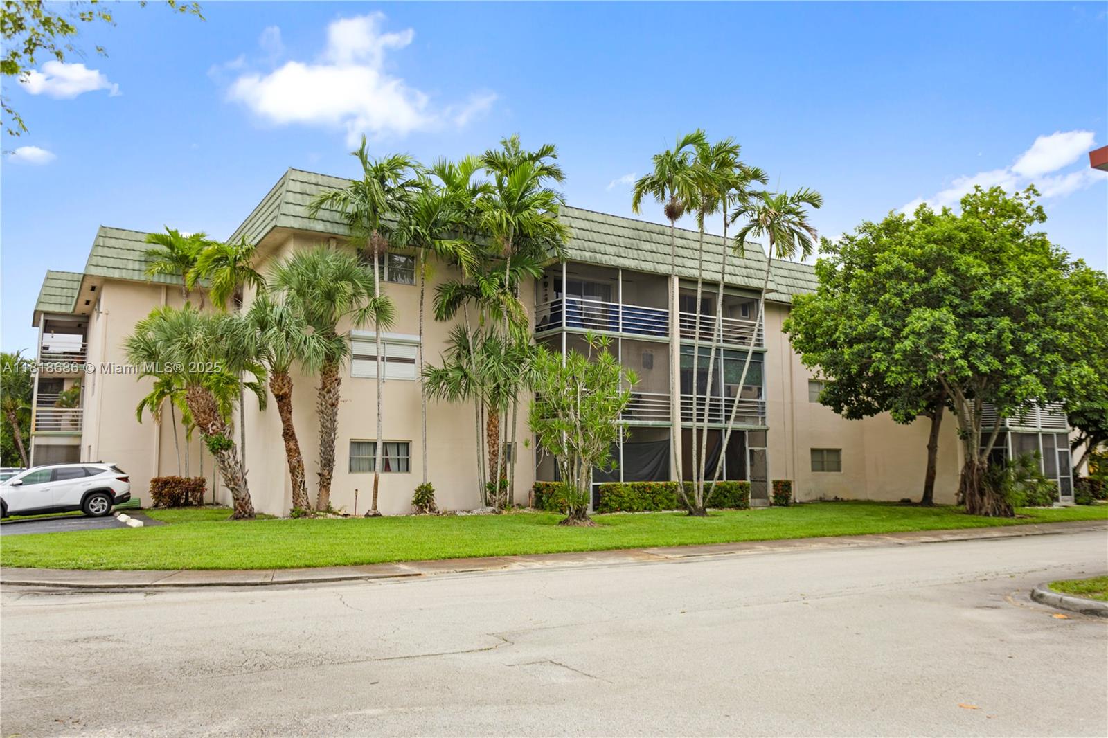 A three-story apartment building with a green mansard roof, palm trees, and a parked car — 5790 Stirling # 212, Hollywood FL 33021, HOLLYWOOD, FL