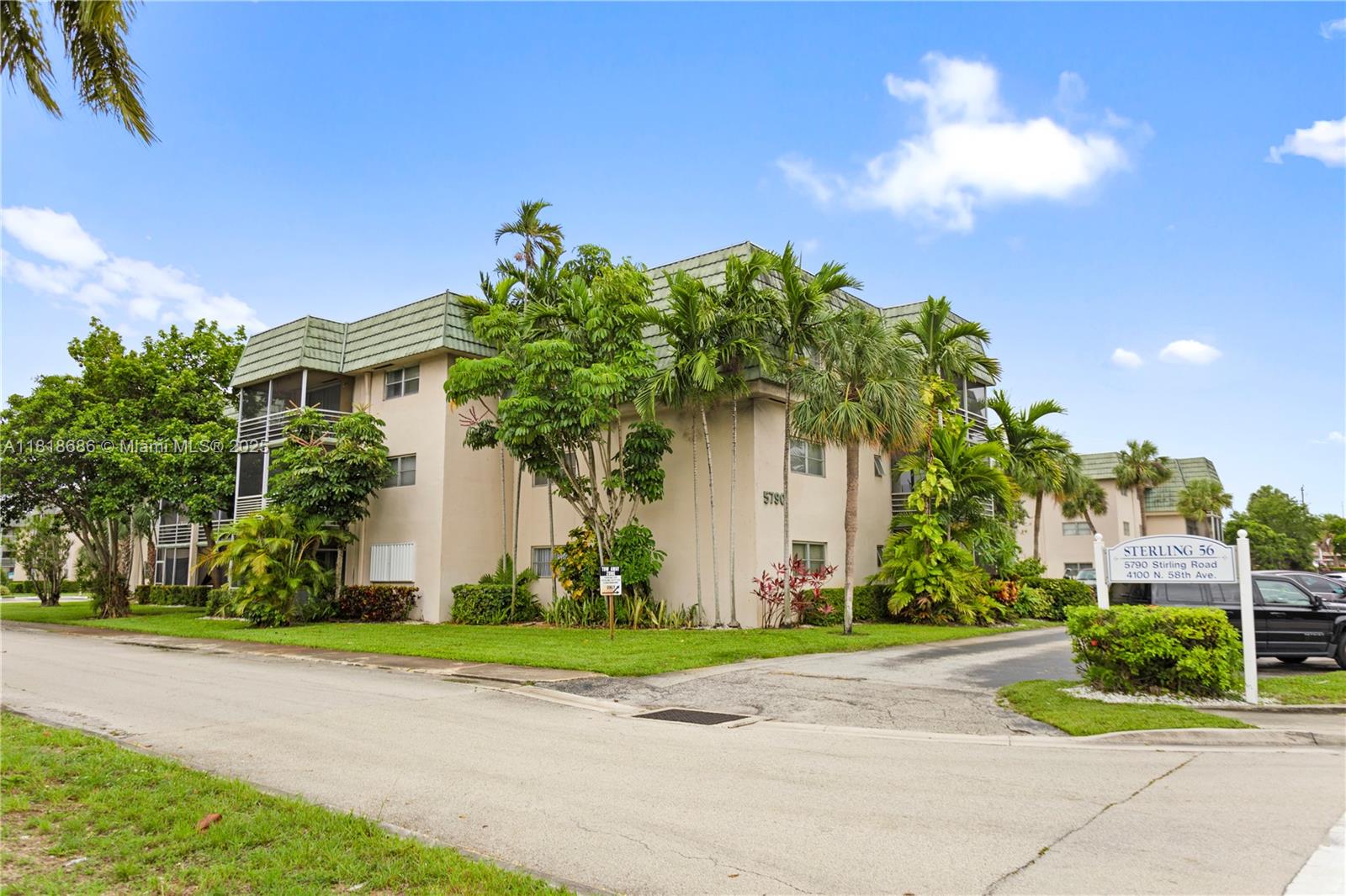 A multi-story apartment building with a green mansard roof is surrounded by palm trees — 5790 Stirling # 212, Hollywood FL 33021, HOLLYWOOD, FL