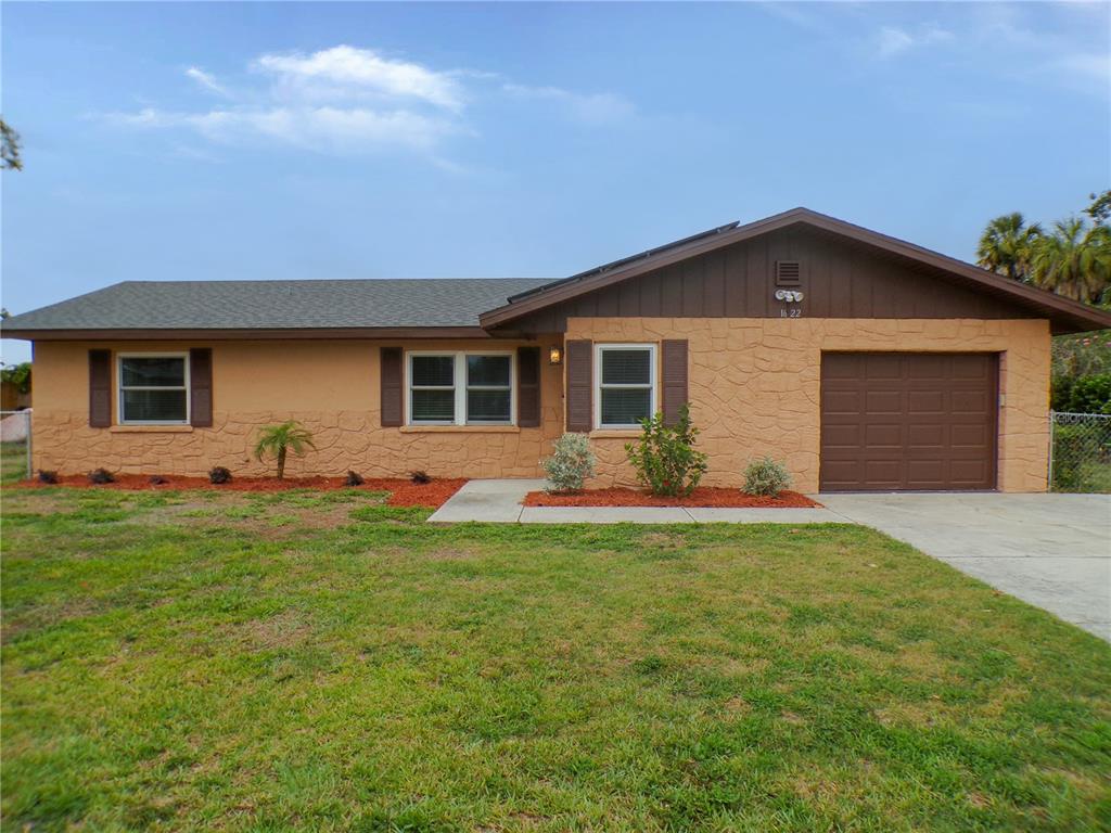 A single-story house with tan textured siding, brown trim, and an attached one-car garage — 1622 17TH STREET E, BRADENTON, FL