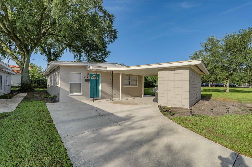 A single-story house with a teal front door and a concrete carport — 434 E ESTHER STREET, ORLANDO, FL
