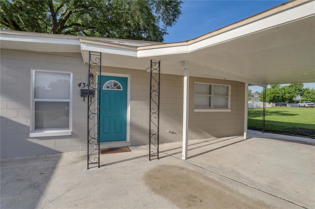 A single-story house exterior features a teal front door, decorative metal columns, and a carport — 434 E ESTHER STREET, ORLANDO, FL