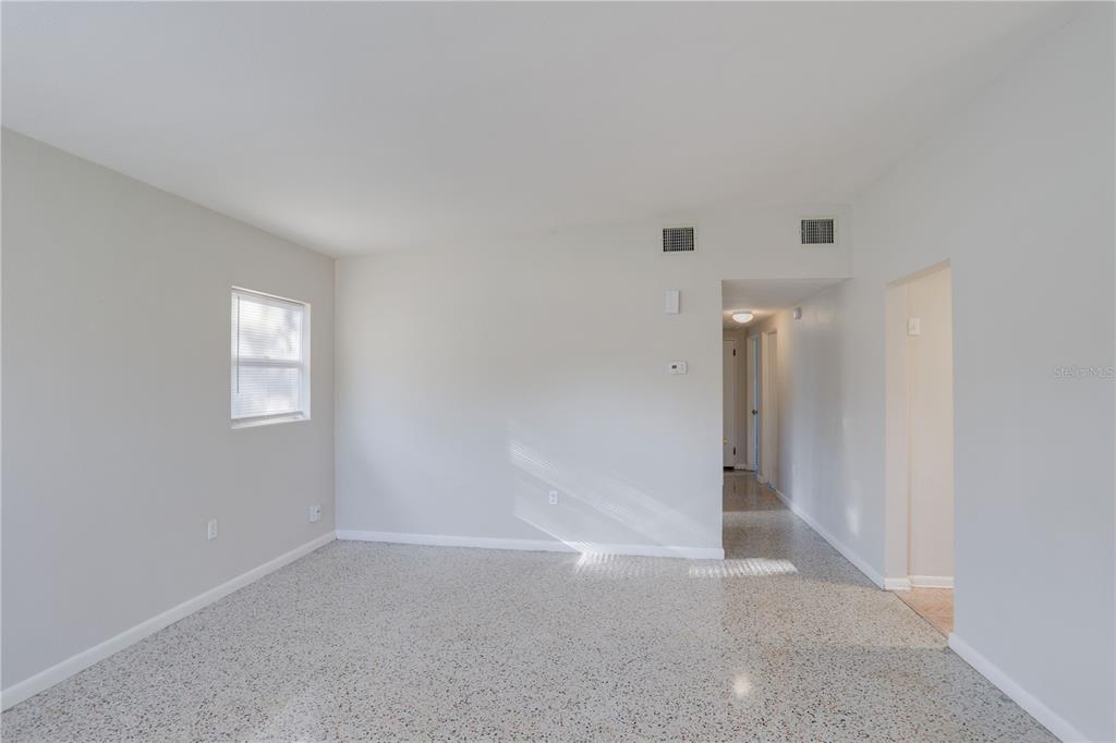 An empty room features light gray walls, a single window, and speckled terrazzo flooring — 434 E ESTHER STREET, ORLANDO, FL
