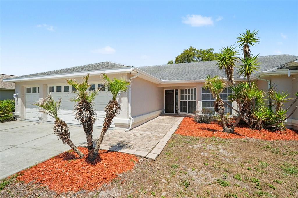A single-story house with a beige stucco exterior, a two-car garage, and a paved walkway — 9389 FOX HOLLOW LANE, WEEKI WACHEE, FL
