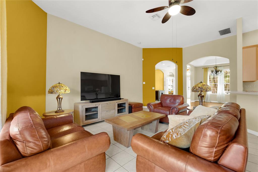 A living room features leather furniture, a wooden coffee table, and yellow accent walls — 730 BRIDGEWAY BLVD, ORLANDO, FL