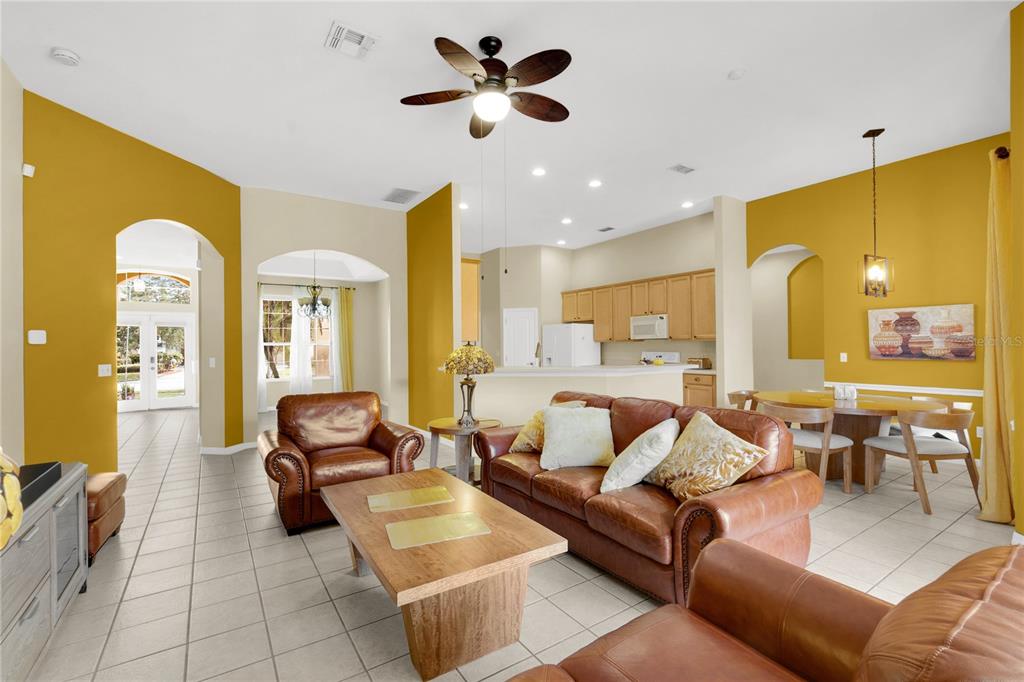 A living room with tile floors, leather furniture, and mustard yellow accent walls — 730 BRIDGEWAY BLVD, ORLANDO, FL