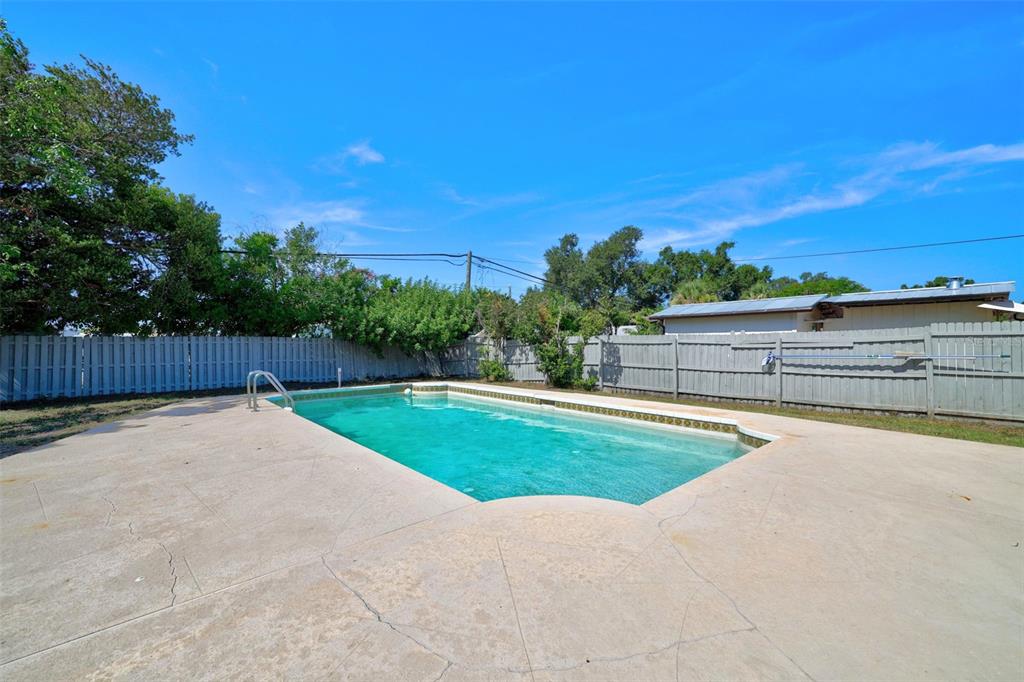 A rectangular swimming pool sits in a backyard enclosed by a wooden privacy fence — 10760 62ND AVENUE, SEMINOLE, FL