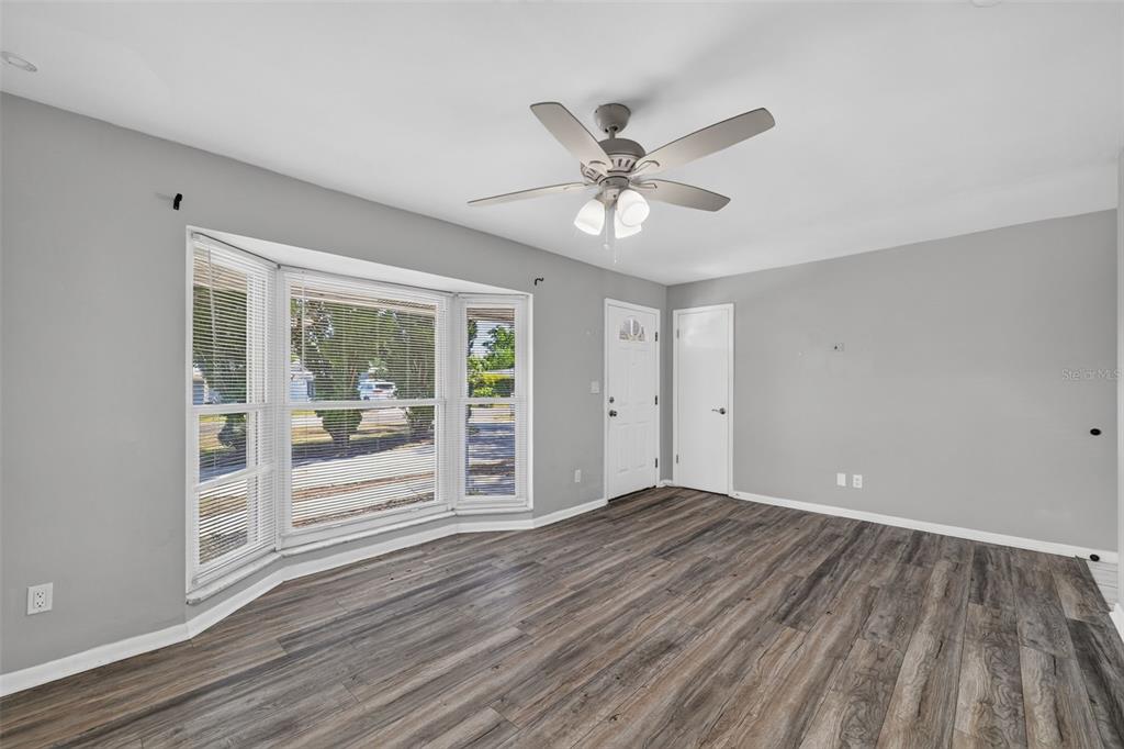 A living room with gray walls, wood-look flooring, a bay window, and a ceiling fan — 10760 62ND AVENUE, SEMINOLE, FL