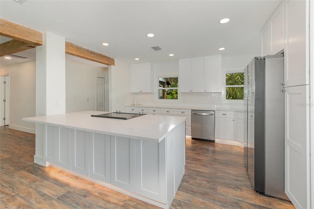 A modern kitchen features white cabinetry, a large quartz island, and wood-look tile flooring — 1770 ALGONQUIN TRAIL, MAITLAND, FL