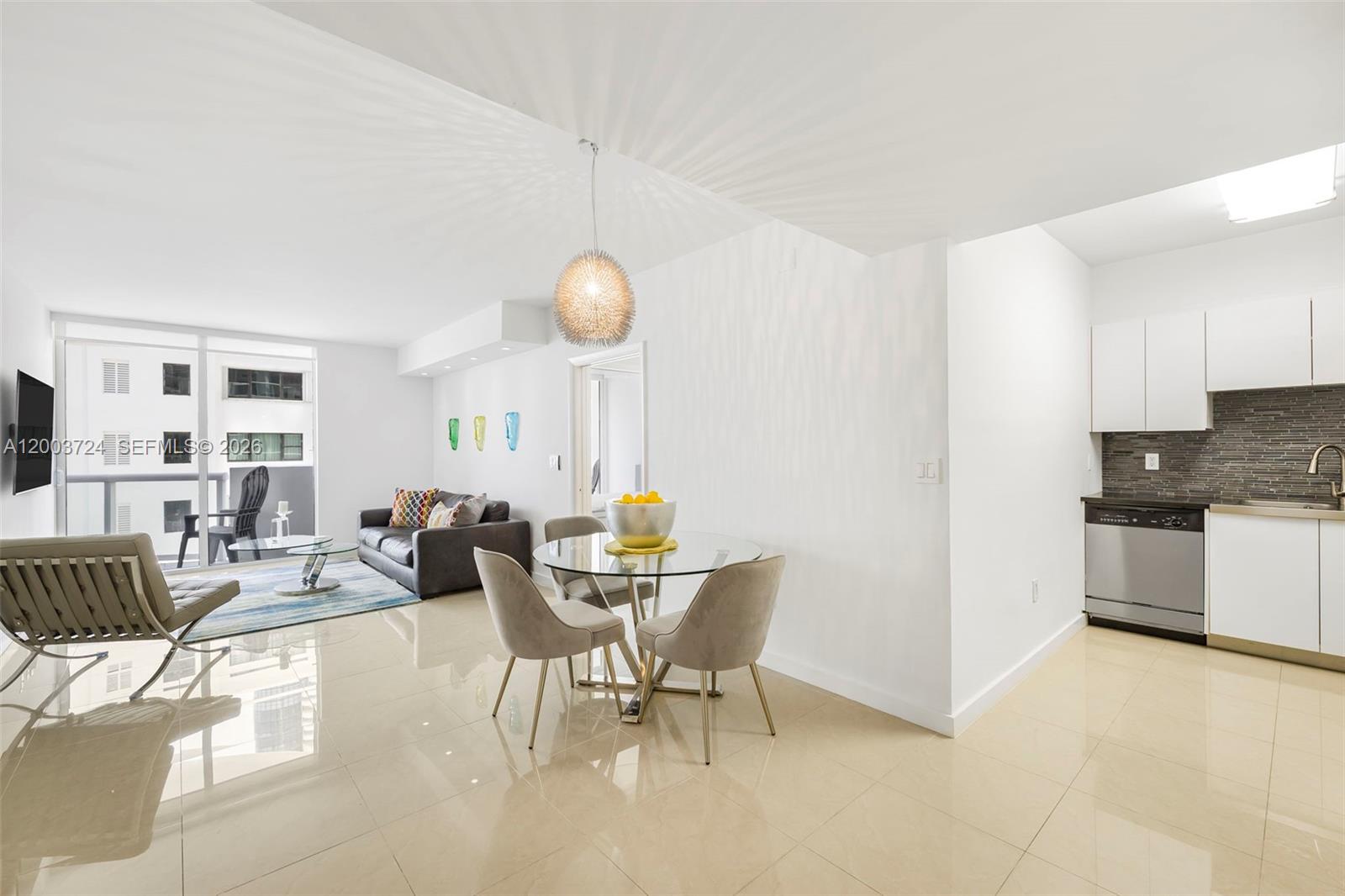 A modern kitchen features white cabinets, stainless steel appliances, black countertops, and a tiled backsplash — 6365 Collins Ave # 805, Miami Beach FL 33141, MIAMI BEACH, FL