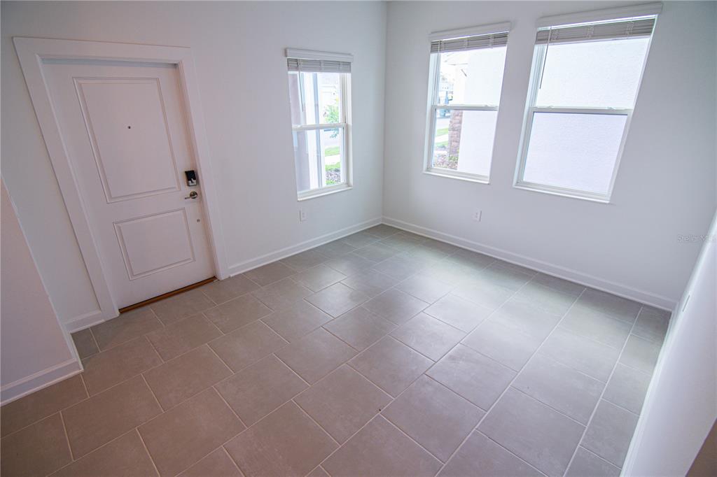 A room with light-colored tile flooring, a white door, and three windows with blinds — 3106 PARK VALE ROAD, ST CLOUD, FL