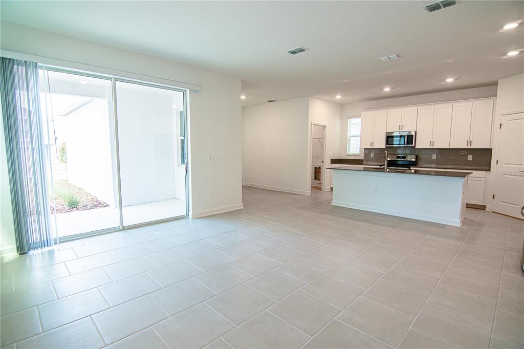 A bright, open-concept kitchen and living area features light tile flooring and white cabinetry — 3106 PARK VALE ROAD, ST CLOUD, FL