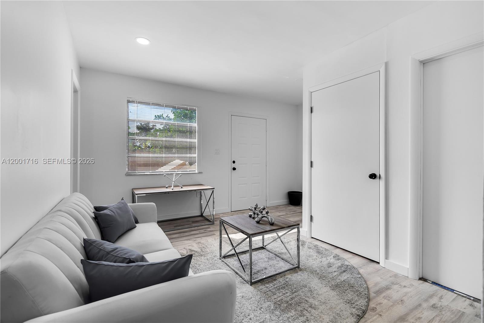 A living room features a white sofa, a coffee table, and light wood-look flooring — 1510 Normandy Dr # A, Miami Beach FL 33141, MIAMI BEACH, FL