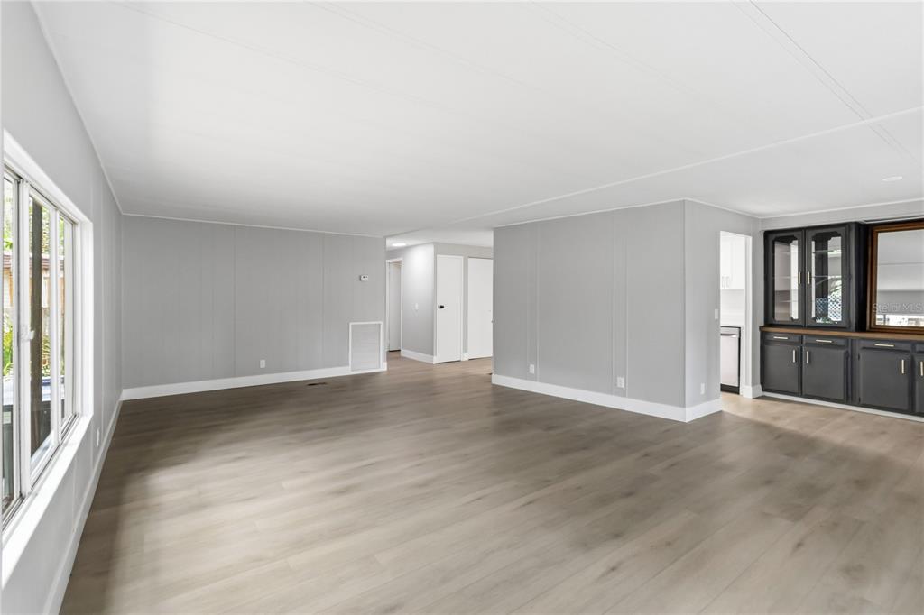 An empty living room with light gray walls, wood-look flooring, and a dark built-in cabinet — 518 W PLANTATION BOULEVARD, LAKE MARY, FL