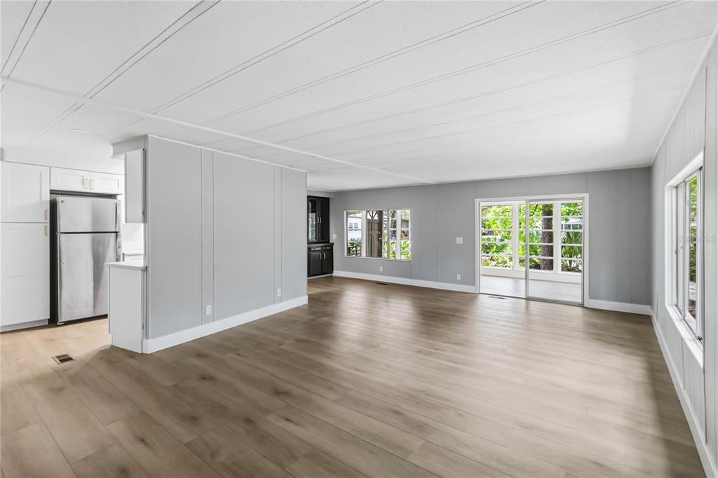 A bright living room with light wood flooring, gray walls, and a sliding glass door — 518 W PLANTATION BOULEVARD, LAKE MARY, FL