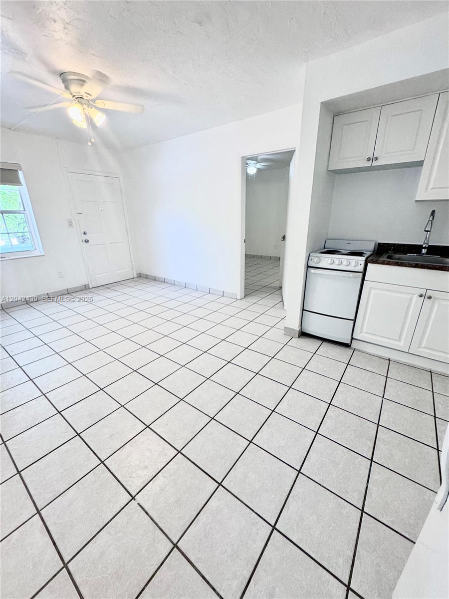 A room with white tiled floors, a ceiling fan, a white door, and a kitchenette — 2732 SW 22nd STREET # 3, Miami FL 33133, MIAMI, FL