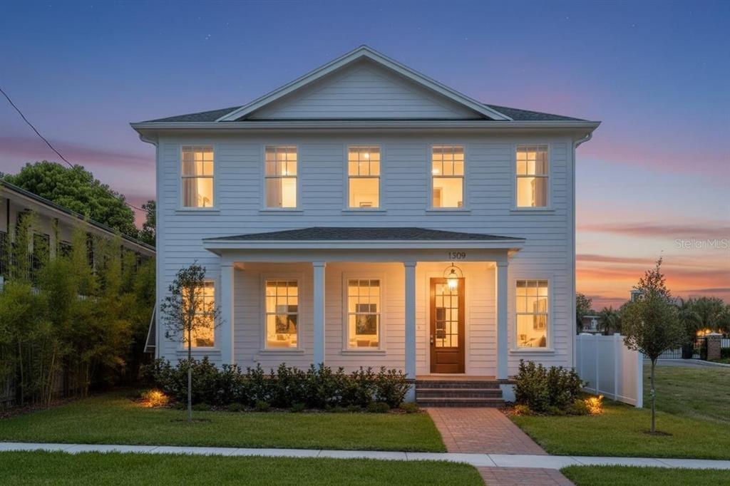 A two-story white house with a front porch and a brick walkway at dusk — 1309 17TH AVENUE N, ST PETERSBURG, FL